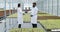 Man and woman in laboratory robes talk to each other standing in the greenhouse. They make a contract and shake hands