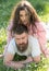 Man and woman laying on grass spring day. Couple on calm faces with daisy flowers in mouth, nature on background. Couple