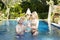 Man and woman, loving couple, in pool in a garden with tropical trees hold glasses with wine in hand