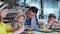 Man and woman with male children enjoy eating tasty juicy burgers with fries sitting at table in cafe