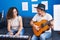 Man and woman musicians playing piano and classical guitar at music studio