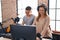 Man and woman musicians playing piano keyboard at music studio