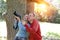 Man and woman near an oak in summer day show to the side and photograph on the big camera