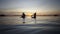 A man and a woman paddle their paddle surfboard towards the shore at sunset