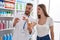 Man and woman pharmacist and client holding pills bottle reading prescription at street