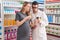 Man and woman pharmacist and pregnant client holding medication bottle speaking at pharmacy
