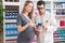 Man and woman pharmacist and pregnant client looking smartphone screen at pharmacy