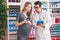 Man and woman pharmacist and pregnant client using smartphone and touchpad speaking at pharmacy