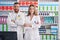 Man and woman pharmacists smiling confident standing with arms crossed gesture at pharmacy