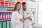 Man and woman pharmacists using touchpad holding pills bottle at pharmacy