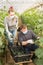 Man and woman in protective medical masks harvest cucumbers in greenhouse