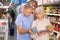 Man and woman purchasers choosing tinned fish in big supermarket