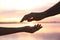 Man and woman reaching hands to each other at sunset, closeup. Nature healing power