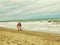 Man and woman in a red dress walk on the sand along the sea