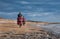 Man and woman riding sandy beach mountain bike with backpack.