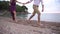 A man and a woman running along the pebble beach holding hands