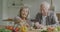 Man and woman senior couple cooking salad and checking recipe with smartphone in kitchen at home