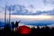 Man and Woman Silhouette by Red Tent with View of Ocean and Islands at Sunrise.