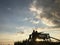 A man and a woman are sitting on a bench against the sunset. Two lovers hug and look into the distance. Silhouette of a couple