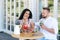 Man and a woman are sitting in a cafe, looking at each other lovingly, eating delicious desserts and drinking cocktails