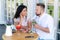 Man and a woman are sitting in a cafe, looking at each other lovingly, eating delicious desserts and drinking cocktails