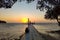 Man and woman sitting on the pear and enjoy the sunrise under the ocean. Silhouettes