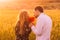 Man and woman smells bouquet of poppies in wheat field on the dusk