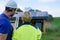 Man and woman solar installers engineers with tablet while installing solar panel system on house, rear view.