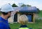 Man and woman solar installers engineers with tablet while installing solar panel system on house, rear view.