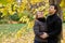 Man and woman stand embracing under maple tree and