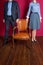 Man and woman standing around empty armchair.