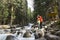 Man and woman standing on the rocks on the Bank of a mountain river among the firs