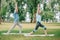 Man and woman standing on yoga mats in warrior poses while practicing yoga in park