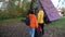 A man and a woman with suitcases and backpacks go to a triangular wooden house.