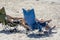Man and woman sunbathe on the beach sitting in tourist folding chairs