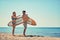 Man and woman surfers walking on the beach