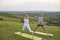 A man and a woman synchronously practice yoga, meditate balance in the pose of standing grass on nature.