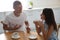 Man and woman talking while drinking tea at table in kitchen