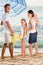 Man and woman with two kids standing together under beach umbrel