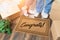 Man and Woman Unpacking Near Welcome Mat with Congrats, Moving Boxes and Plant