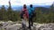 A man and a woman view their surroundings from above while hiking