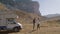 Man and woman walk through countryside with mountains while traveling by camper car rbbro.