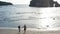 Man and Woman Walking Along Tropical Beach at Sunset, Tracking aerial shot of young couple on vacation having fun on the