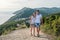 Man and woman walking hug on a mountain with seascape. Front view.