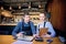 Man and woman wearing apron doing accounts after hours in a small restaurant. Employees checking monthly reports