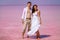 A man and a woman in white clothes in the afternoon on a salty pink lake