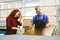 Man and woman working on glass pane in glazier workshop