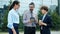 Man and women colleagues talking outdoors looking at tablet screen smiling