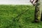 Man in work clothes mows green grass with a trimmer