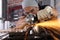 Man work in home workshop garage with angle grinder, goggles and construction gloves, sanding metal makes sparks closeup, diy and